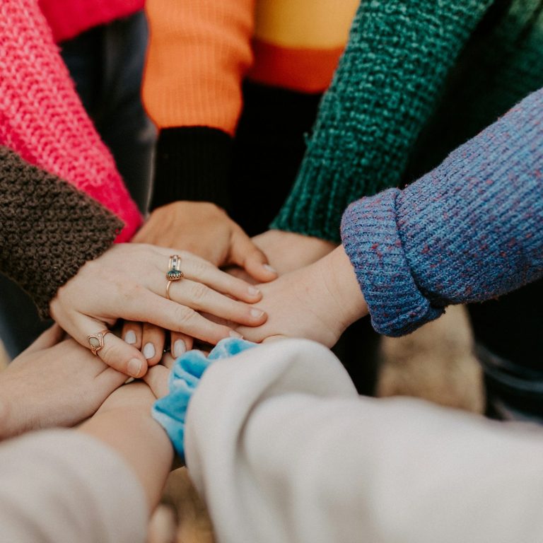 Foto Menschen die im Kreis Hände aufeinander legen Bildausschnitt von Menschen die im Kreis stehen und die Hände aufeinander legen.